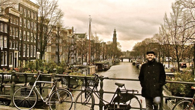 man leaning on bridge railing amsterdam
